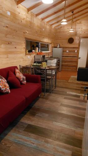 达卡卫Cabañas El Roble的一间带红色沙发的客厅和一间厨房