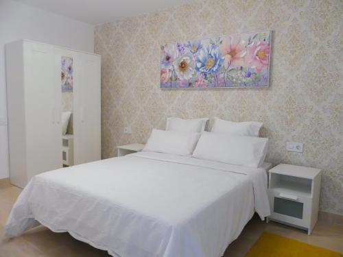莫甘Apartamentos Guadalupe Gran Canaria Puerto Rico的卧室配有白色的床和墙上的绘画作品
