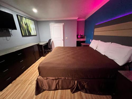 BellBELL RESORT MOTEL的一间卧室配有一张大床和紫色照明