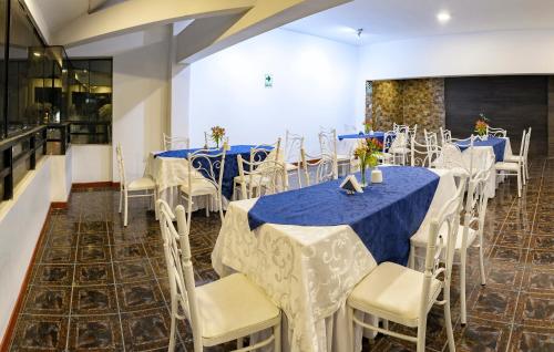 万卡约Hotel Huaytapallana suites的宴会厅配有蓝色和白色的桌椅