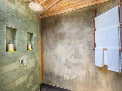 乌鲁瓦图Wisnu Lumbung Uluwatu的墙上设有淋浴和毛巾的浴室