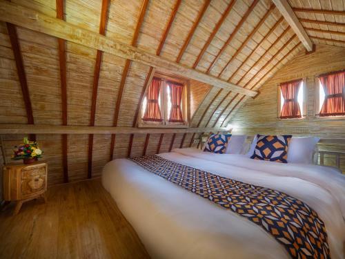 乌鲁瓦图Wisnu Lumbung Uluwatu的木制客房内的一间卧室,配有一张床