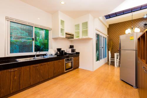 奥南海滩宜拉瓦房屋酒店的厨房配有木制橱柜和不锈钢冰箱。
