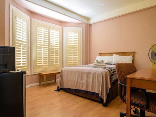 旧金山Elite Inn的卧室配有一张床、一张书桌和窗户。
