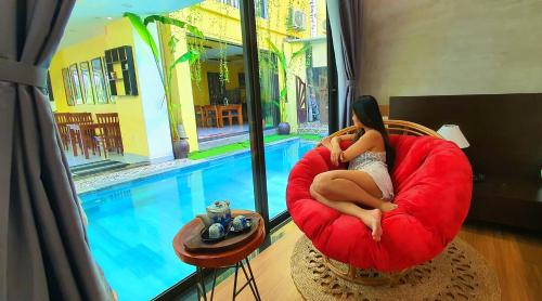 会安PHỐ CHỢ ĐÊM Villa - Near Hoi An Old Town 200m的坐在游泳池旁红椅上的女人