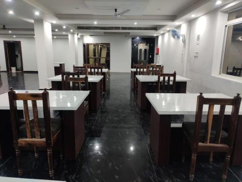 王舍城Hotel Shree Krishna Palace的餐厅设有白色的桌子和木椅