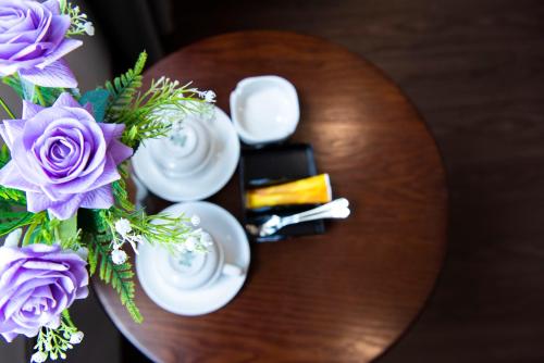 Xóm NiêmGia Phong Hotel的一张木桌,上面有紫色花瓶
