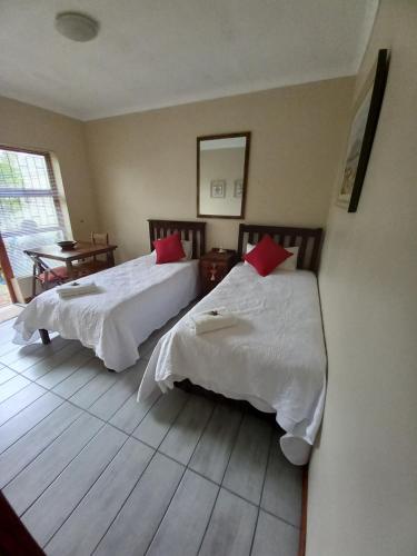 乔治Willow Cottage George的一间卧室配有两张带白色床单和红色枕头的床。