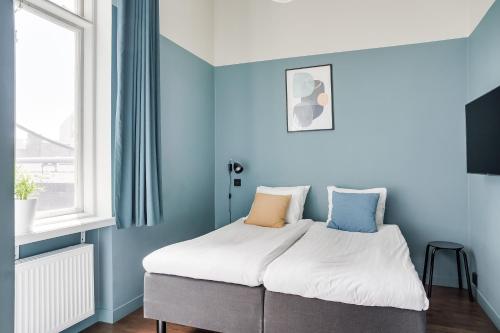 马尔默Forenom Aparthotel Malmö Varvsstaden的蓝色墙壁间的一张床