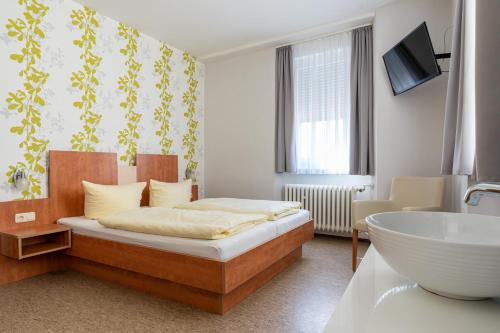 吕德斯海姆科隆路德施姆酒店的一间卧室配有一张床、一个浴缸和一个水槽