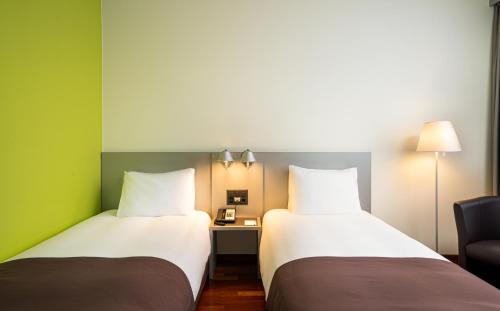 苏黎世Holiday Inn Zürich Messe, an IHG Hotel的两张睡床彼此相邻,位于一个房间里
