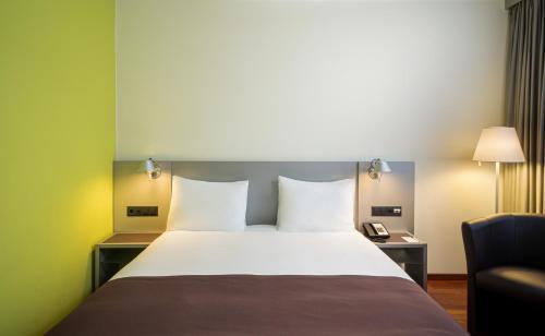 苏黎世Holiday Inn Zürich Messe, an IHG Hotel的配有一张床和一把椅子的酒店客房