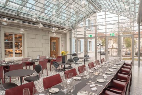 穆里CASPAR Swiss Quality Hotel的一间带桌椅和玻璃天花板的用餐室