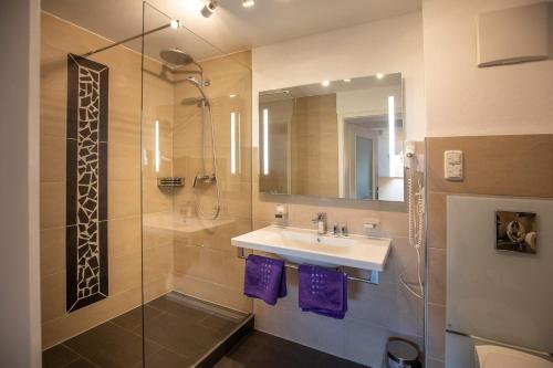 里姆斯廷格Berg Hotel Weingarten Garni的浴室配有水槽和带紫色毛巾的淋浴