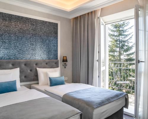 克拉科夫Merci Boutique Hotel的配有窗户的酒店客房内的两张床