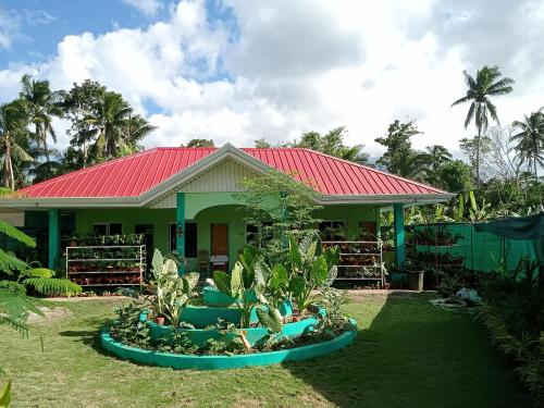BatuanBARRIL GREEN HOMESTAY的一座有红色屋顶和一些植物的房子