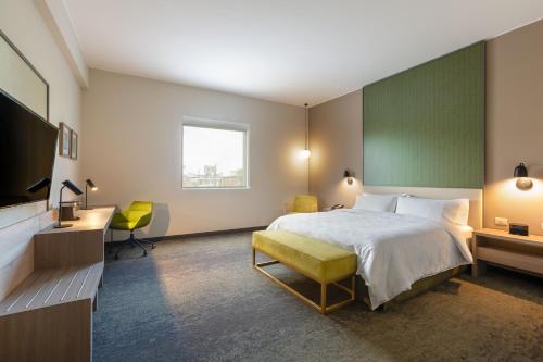 皮乌拉Holiday Inn - Piura, an IHG Hotel的酒店客房设有一张床、一张书桌和一台电视机。