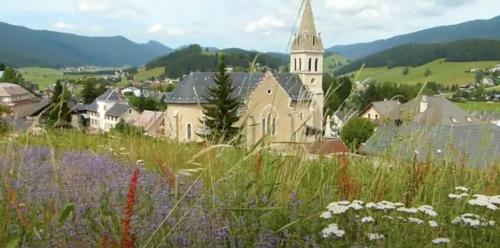 梅奥德尔Gîte La Grange的一座教堂,位于一座小山上,有一片花田