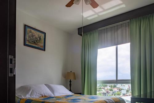 圣何塞Lujoso condominio con lavadora y secadora, S. José的一间卧室设有床铺和一个带绿色窗帘的窗户。