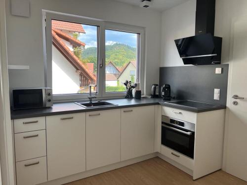 哥根巴赫Black Forest Apartments的一间厨房,配有白色的橱柜和大窗户