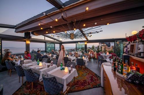 伊斯坦布尔伊斯坦布尔特里亚酒店的一间设有白色桌子的餐厅,有坐在桌子上的人
