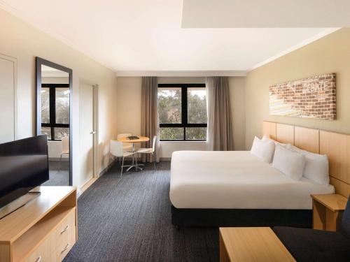悉尼Mercure Sydney Macquarie Park的酒店客房,配有床和电视