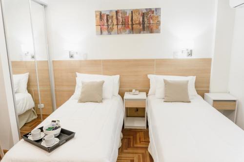 罗萨里奥Mediterráneo Hotel y Spa的配有白色床单的客房内的两张床