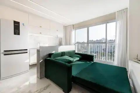 里约热内卢Suite Verano Stay的客厅在窗户前设有绿色沙发
