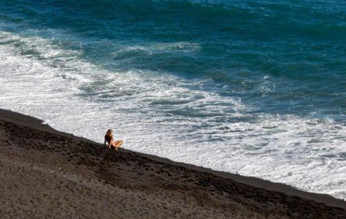 坎德拉里亚THE DRAGONFLY Private Loft 100m Beach的坐在海滩上看着大海的女人