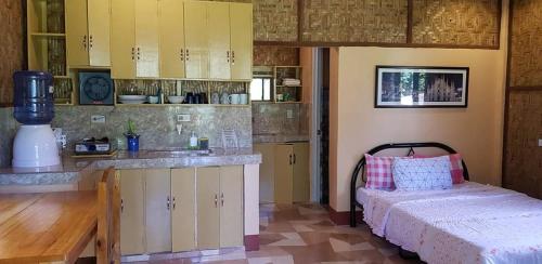 曼巴豪Paco's Garden Home Stay的一间厨房,配有黄色橱柜和一张位于客房内的床
