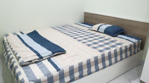 河内Era Apartment Xuân Thuỷ的一张带蓝色和白色床单的床,床上配有枕头