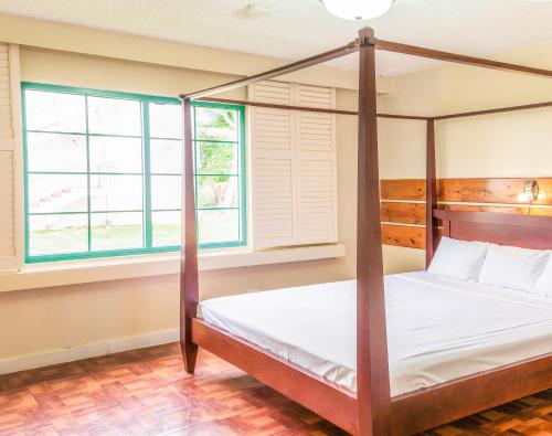 塔穆宁花园别墅酒店的一间卧室设有四柱床和两个窗户。