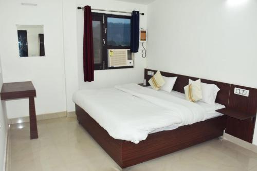JhirnaCorbett Bhavesh home Stay的一张铺有白色床单的床和一个窗户