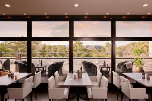 吹田南千里水晶酒店的餐厅设有桌椅和大窗户。