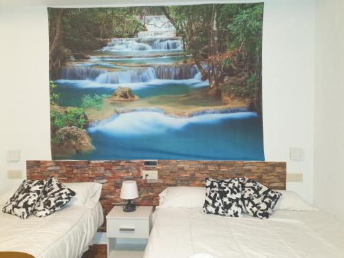 Peal de BecerroHotel Al-Ándalus Peal, en Cazorla Comarca的客房设有两张床,并画了瀑布