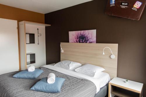 格罗宁根Hotel The Happy Traveler的一间卧室配有一张带两个蓝色枕头的床