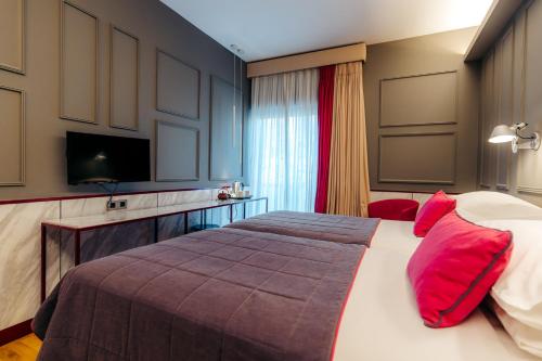 雅典海洛狄恩酒店的一间卧室配有一张带红色枕头的大床