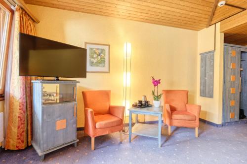 采尔马特西米酒店的一间设有两把椅子、一张桌子和一台电视的房间