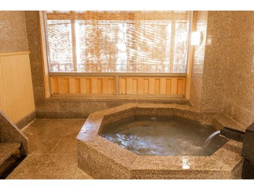伊势市Hotel Castle Inn Ise Meotoiwa的带窗户的浴室内的大石头浴缸