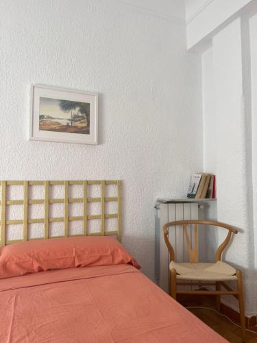 萨拉戈萨Apartamento Único en Plaza del Pilar的一间卧室配有一张床、一把椅子和一张照片