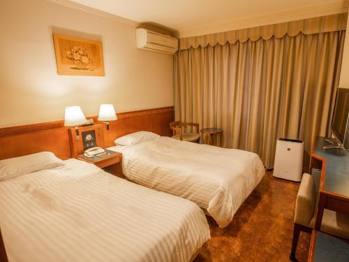 铃鹿市Hotel Castle Inn Suzuka Chuo的酒店客房设有两张床和电视。