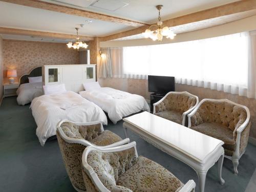 四日市Hotel Castle Inn Yokkaichi的酒店客房,配有两张床和两把椅子