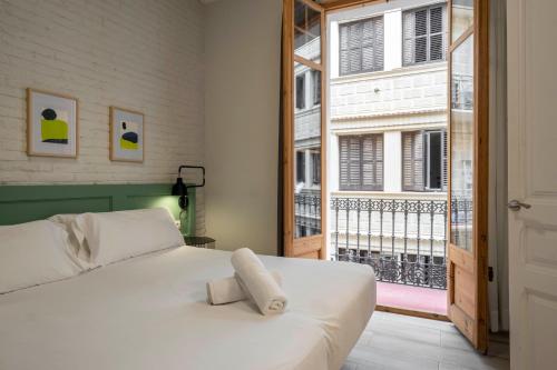 巴塞罗那Aspasios Gracia Apartments的卧室设有白色的床和大窗户