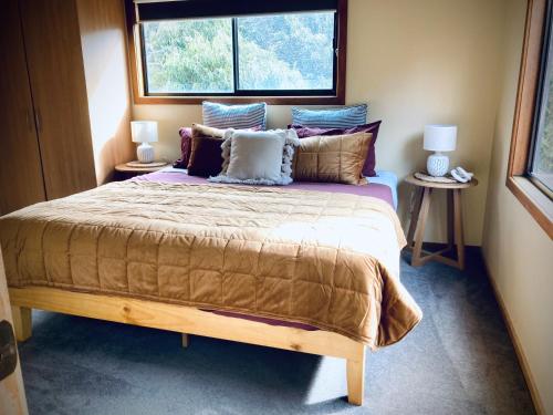 坎贝尔港坎贝尔港-大洋路-红雪松度假屋的卧室配有带枕头的大床和窗户。