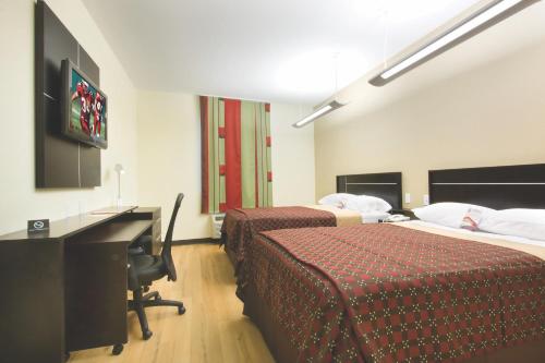 博蒙特Red Roof Inn & Suites Beaumont的酒店客房设有两张床、一张桌子和一台电视。