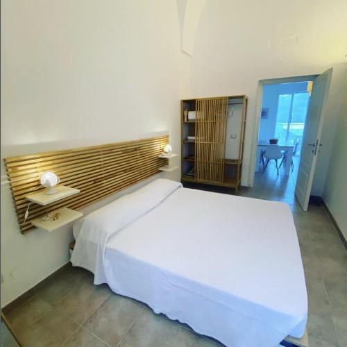 莱切省卡斯特罗RESIDENCE IL GIARDINO DI DONNA LEDA的卧室配有一张白色的大床和一张桌子