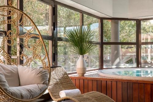 圣拉斐尔Golf Hôtel de Valescure & Spa NUXE的客房设有椅子和一个带窗户的浴缸
