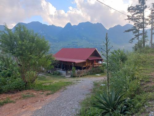 河江Homestay Hoàng Vũ的一座有红色屋顶的建筑,背景是群山