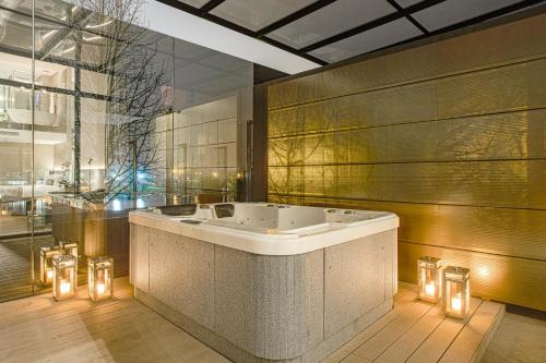 PinhaisSuryaa Hotel Pinhais, Curio Collection by Hilton的浴室配有带灯的浴缸。
