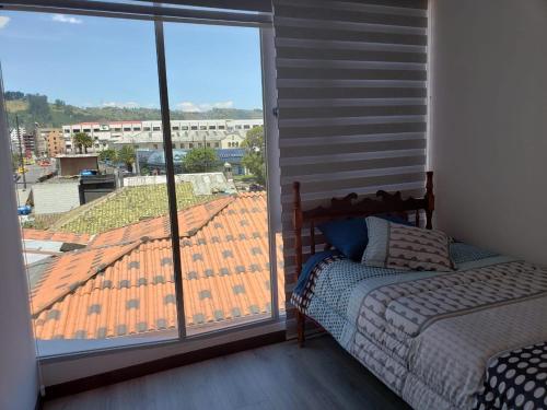 基多Hermoso departamento, céntrico y tranquilo的一间卧室设有一张床和一个大窗户